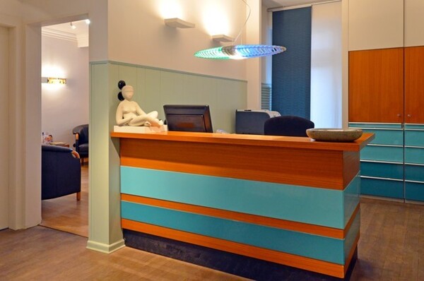 Moderne Arztpraxis mit Empfangstresen, Computer, Wartebereich und stilvoller Dekoration.