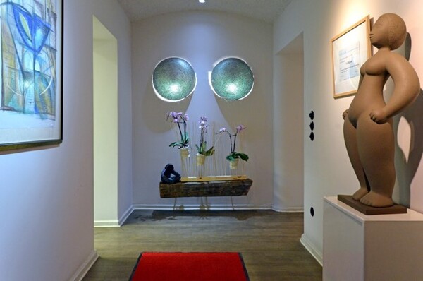 Moderner Flur mit Holzfußboden, rotem Teppich, Kunstwerken und dekorativen Pflanzen.